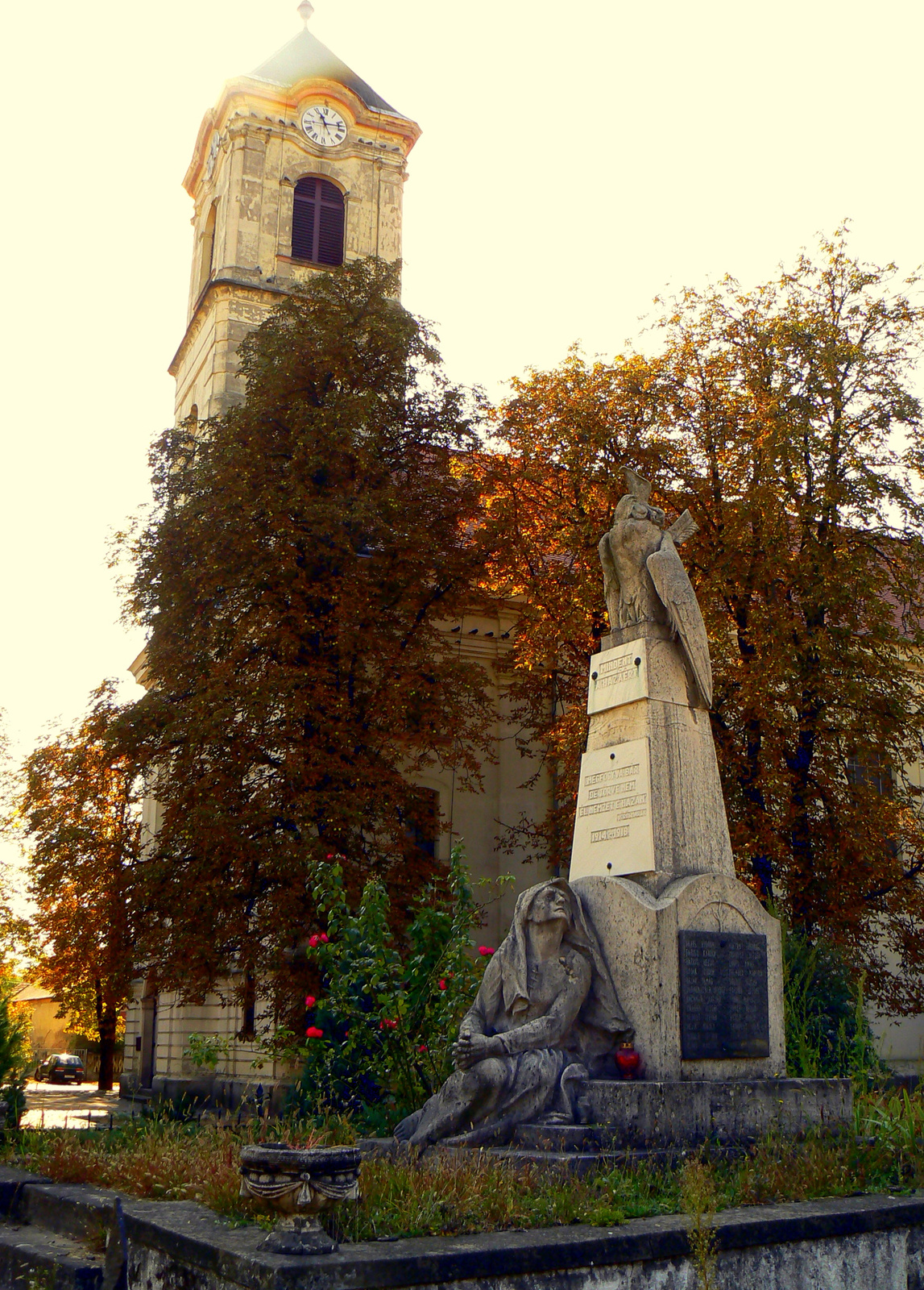 Római katolikus templom, előtérben a háborús hősök szobrával (Pi