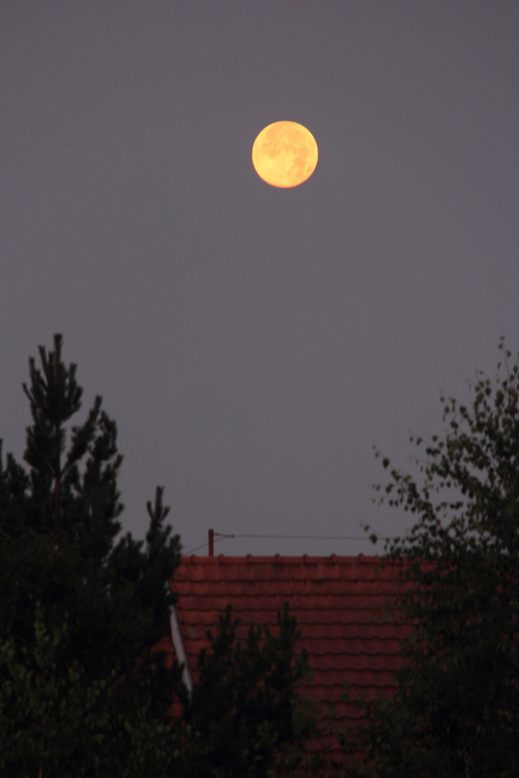 Hajnali háztető fölött a Hold