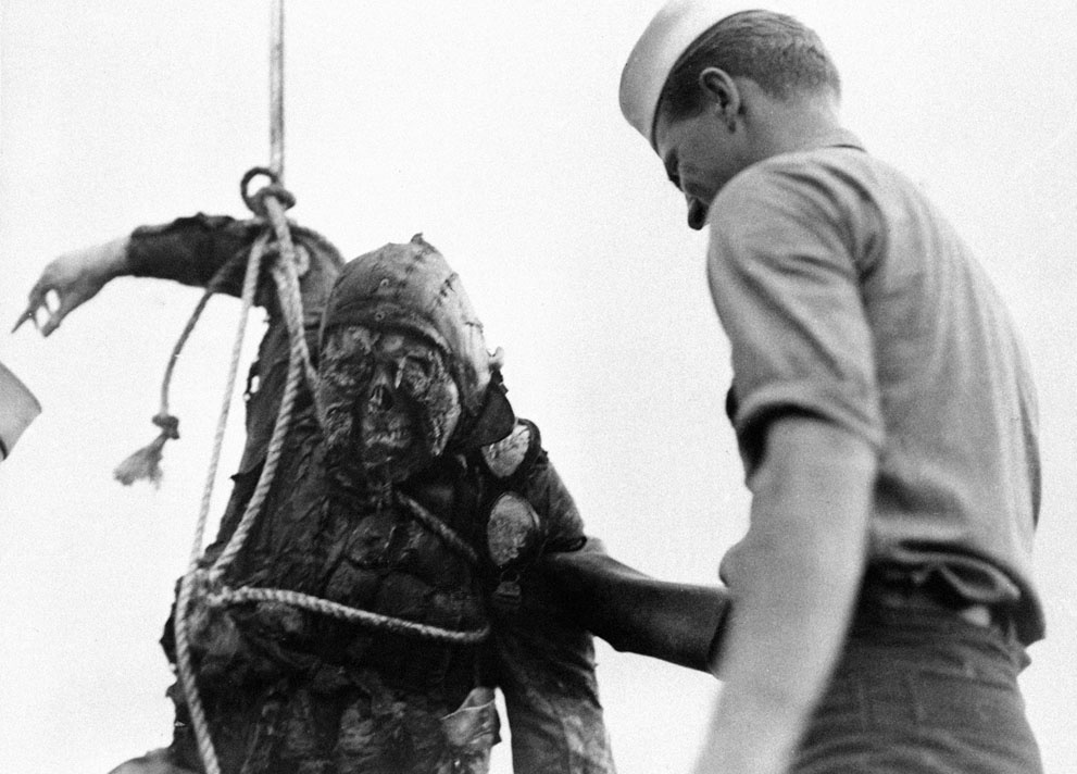 An American seaman looks at the charred corpse of a Japanese fli