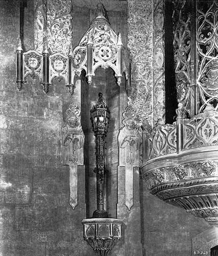 A detail shot of a light fixture flanked by two devote monks.