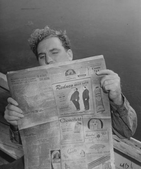 A man reading the newspaper which shows a before and after pictu