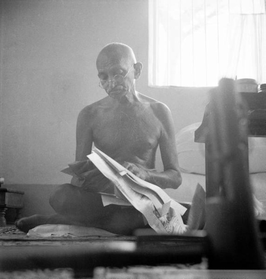 Indian leader Mohandas Gandhi reading as he sits cross-legged on