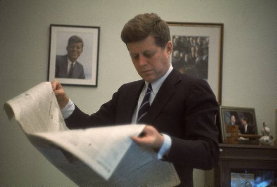 President John F. Kennedy reading a newspaper in his White House