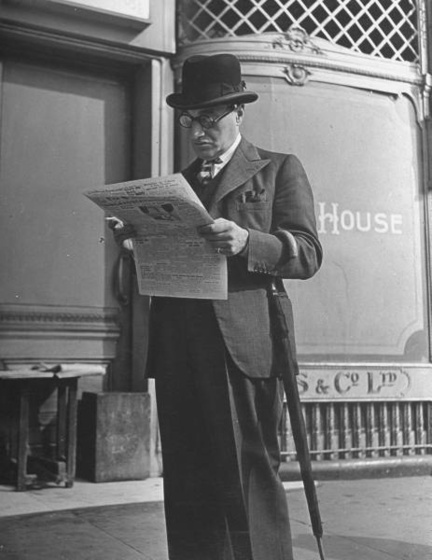 Typical English Londoner w. homburg hat &amp; umbrella reading n